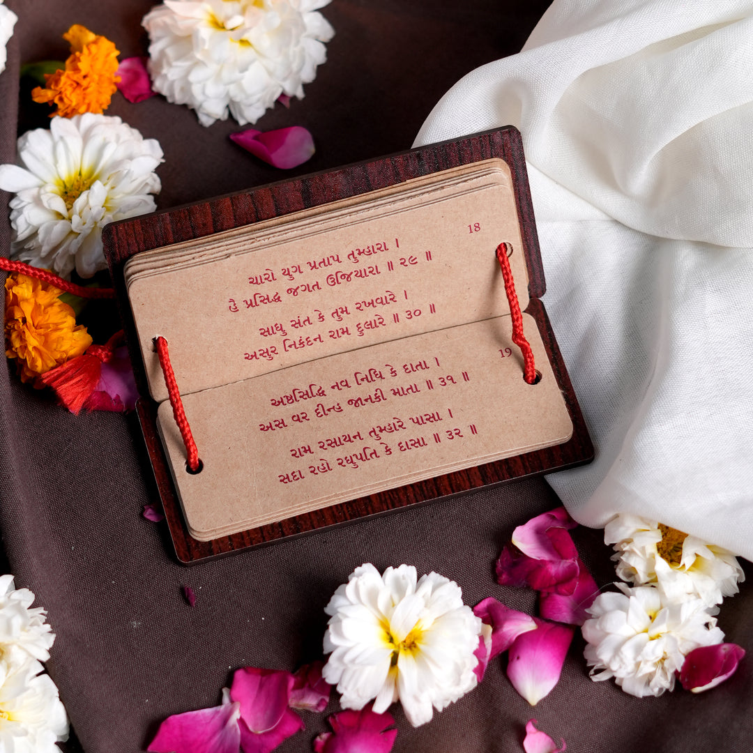 Spiritual Gujarati Hanuman Chalisa booklet placed in a temple setting with diya